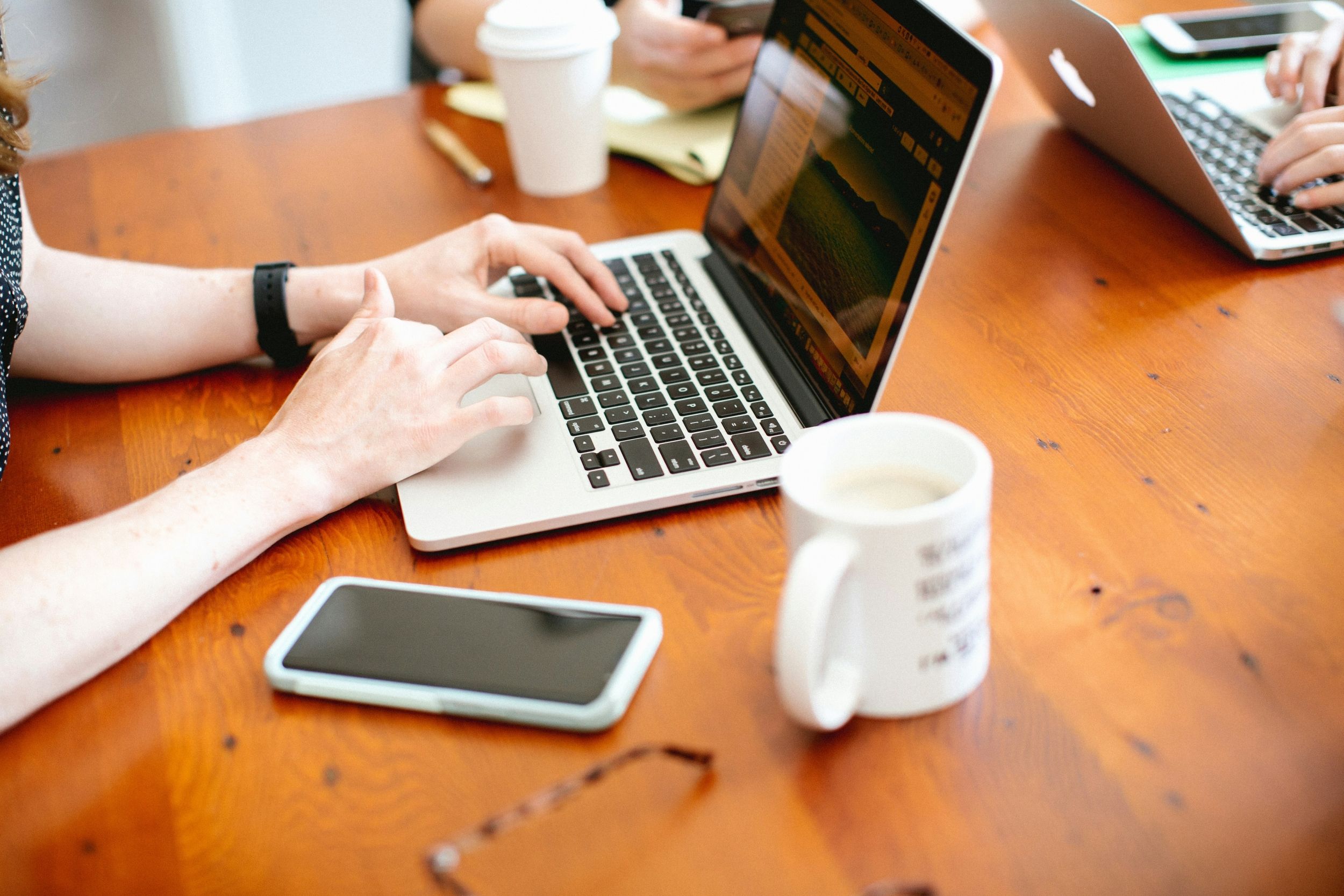 1749775566_close-people-working-laptops-wooden-table.jpg