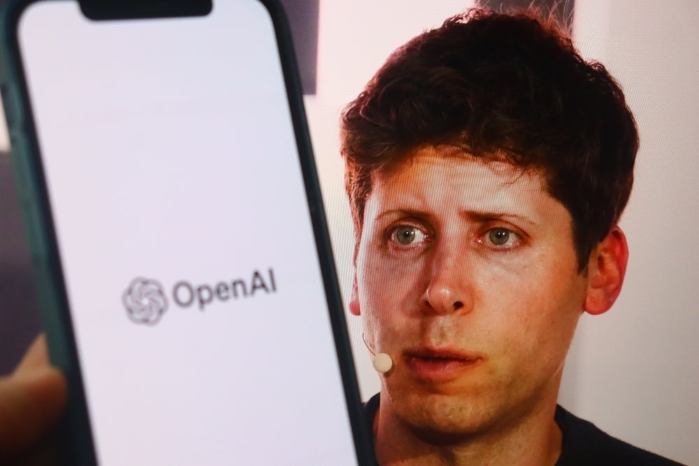 Sam-Altman-With-Openai-Blurry-Logo-Backg.jpeg
