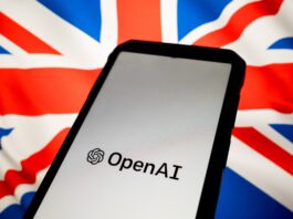 A phone displaying the OpenAI logo in front of the union jack flag.