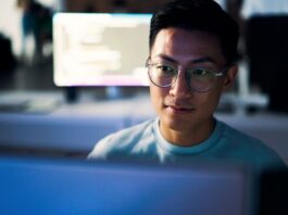 A person sitting at a desk and looking at a computer screen.
