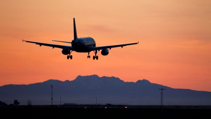 gettyimages-183409311.jpg A passenger jet comes in for a landing, silhouetted against a dark pastel skyscape