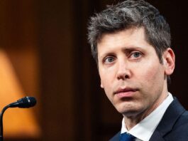 Sam Altman, a white man with graying dark hair, sits in front of a microphone.