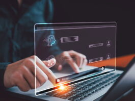 a person taping on laptop keyboard with AI conversation on hologram UI