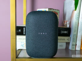Pictured is the gray Google Nest Audio on a bookshelf with the lights blinking.