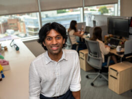 A researcher poses in front of a lab with computers. 