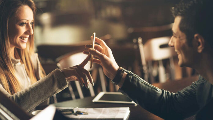 eF5AUP9YhkmJyLuVsQBN7f.jpg A man and a woman on a date looking at a phone