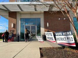 Woman enters a polling location inside a mall to cast a ballot in the November 8, 2022 midterm election while two other women examine a ballot drop box.