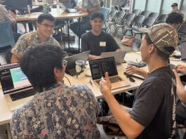 people working on computers sitting around a table