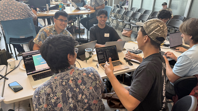 people working on computers sitting around a table