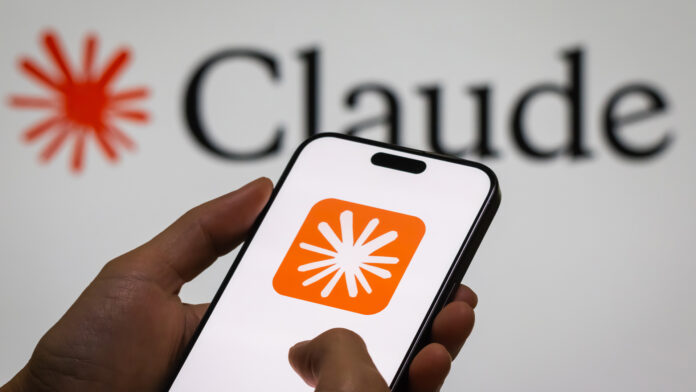 nBgbYBKj4tUofQNaYdx3mX.jpg Anthropic logo symbol on a smartphone screen with Claude AI model logo and branding pictured in background.