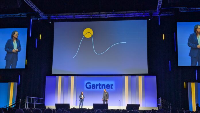 Christine Lee, VP research at Gartner and Leigh McMullen, distinguished VP analyst at Gartner onstage at Gartner Security &amp; Risk Management Summit in London, stood beneath a large screen showing a Gartner hype cycle diagram.