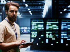 Experienced engineer writing data center disaster recovery plan on laptop to provide rapid restoration of service, limiting disruption and minimizing interruptions to normal operations