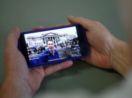 An AI-generated video of London in decline, shared on the social media site X account of British far-right activist Tommy Robinson, is viewed on a smart phone in London