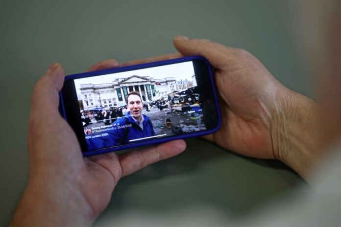 76b168bca4ce97d96418cef312ae3da319fbddd3.jpg An AI-generated video of London in decline, shared on the social media site X account of British far-right activist Tommy Robinson, is viewed on a smart phone in London