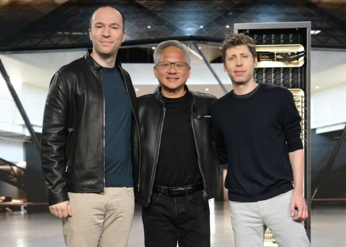 Three people wearing jackets standing in front of an NVIDIA server rack.