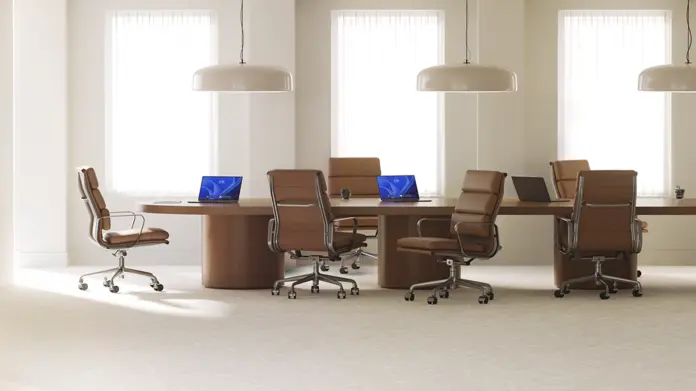 MLSD-Article-BDM-building-enterprise-AI.webp Three open laptops, with two displaying Windows blue bloom backgrounds, sit on a long wood conference room table surrounded by six brown leather office chairs