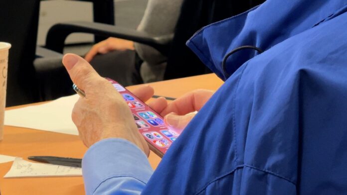Seniors-learn-about-emerging-tech.jpeg An attendee at the Albany Guardian Society AI and Aging symposium navigates apps on his iPhone.