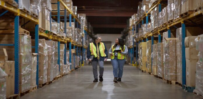 Warehouse-workers-walking-through-the-aisle-manager-reviewing-and-sharing-data-real-time1.jpg 3 ways to navigate changing tariffs with AI agents