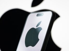In this photo illustration, the logo of Apple Inc. is displayed on a smartphone screen, with the company's iconic black apple symbol visible in the background.