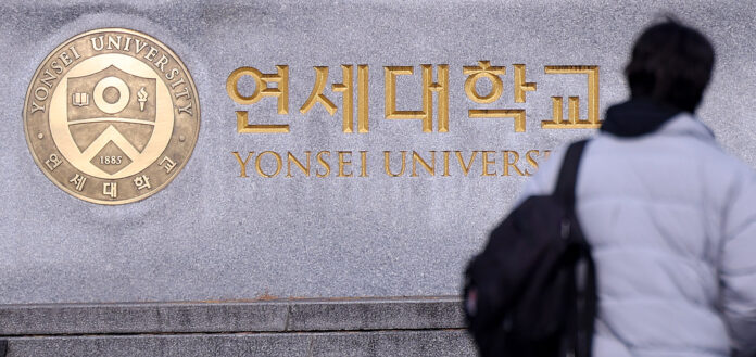 A pedestrian walks by a plaque of Yonsei University in western Seoul. [NEWS1]