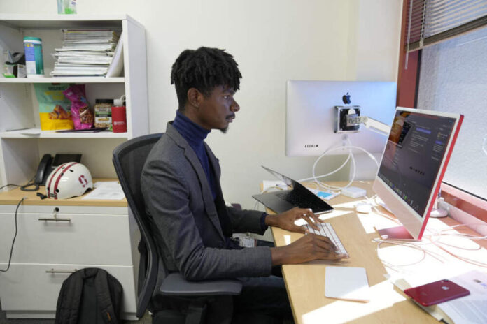 Post-doctoral researcher Tofunmi Omiye works in his office at the Stanford School of Medicine in Stanford, Calif., Tuesday, Oct. 17, 2023. A new study, co-led by Omiye, cautions that popular chatbots are perpetuating racist, debunked medical ideas, prompting concerns that the tools could worsen health disparities for Black patients. (AP Photo/Eric Risberg)