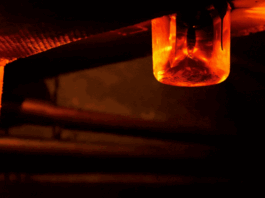 Close-up of a rotating red emergency siren lamp on the wall of a dark tunnel.