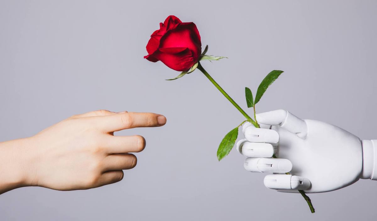 robots-love.jpg human hand reaching for red rose in robotic hand