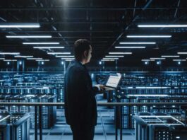 Data Center Male Administrator Using Laptop Computer. Maintenance Specialis working in Cloud Computing Facility on Cyber Security and Network Protection. Server Farm Analytics. Medium Wide