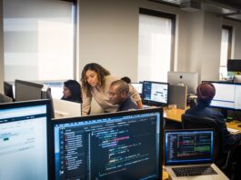 A team of workers sit at their computers collaborating.