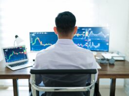 Person working at desk with multiple monitors.