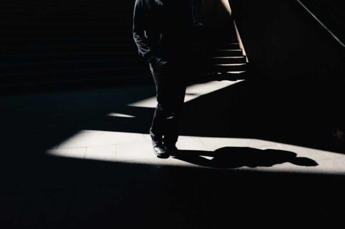 Man walking in shadows at bottom of stairs, visualizing a shadow AI agent