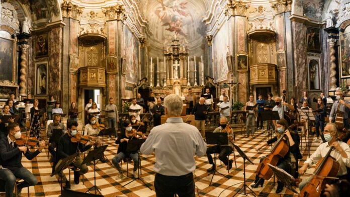 Conductor in front of an orchestra in an ornate concert hall