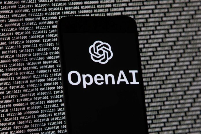 The OpenAI logo appears on a mobile phone in front of a computer screen with random binary data, March 9, 2023, in Boston. (Michael Dwyer/AP)