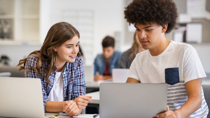 Young people using laptops in a classroom.