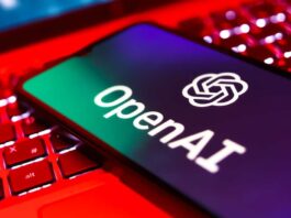 OpenAI logo on a phone screen on top of an open laptop keyboard