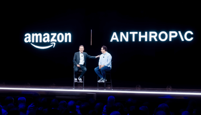 Two men sitting on stools on a stage with amazon and ANTHROPIC logos displayed on a black background.