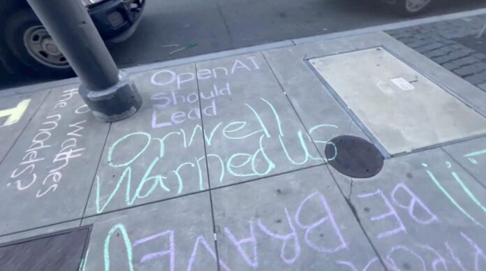 Chalk writing on a sidewalk reads, "OpenAI Should Lead Orwell Warned Us," with additional partially visible words and passing cars nearby.