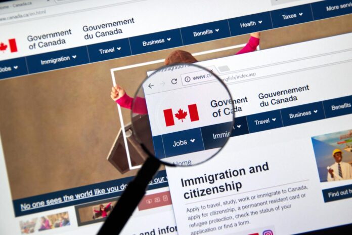 The Government of Canada website, including its immigration and citizenship page, is displayed under a magnifying glass in Montreal, Canada, Nov. 17, 2017. (Adobe Stock Photo)