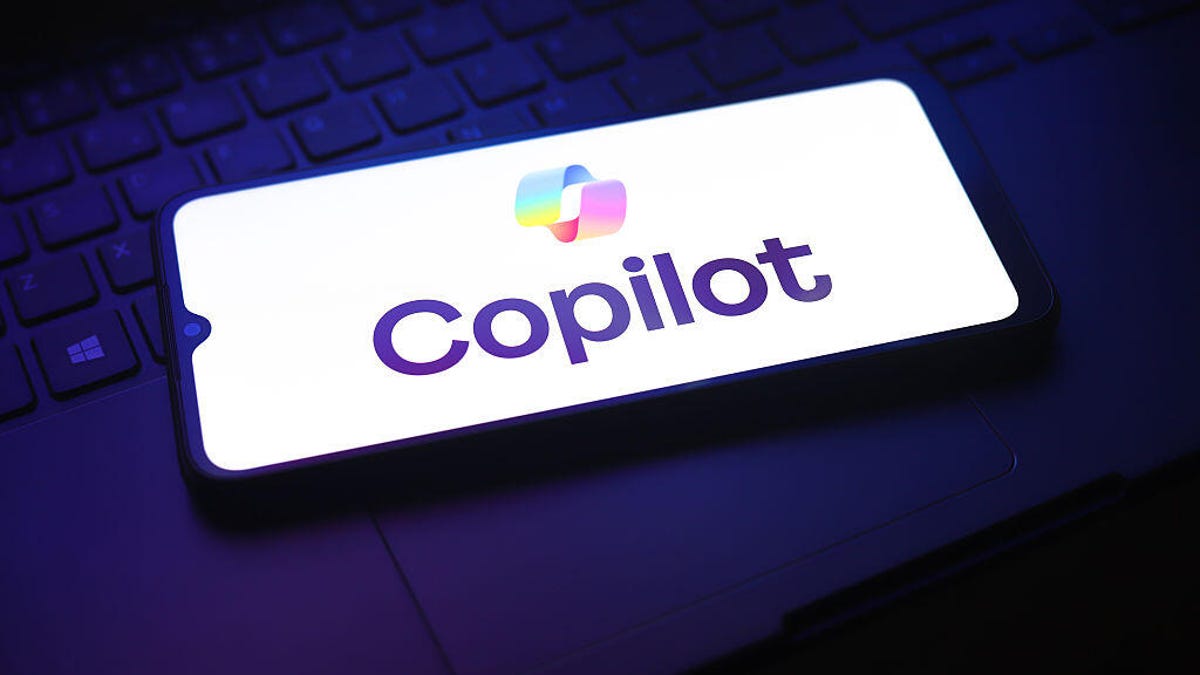 gettyimages-2251534549.jpg A phone on a laptop shows the Copilot logo on a white screen.